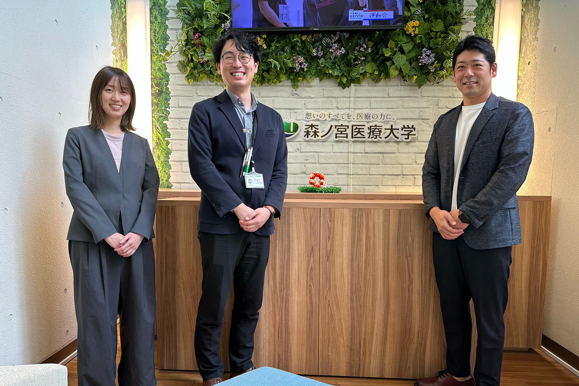 森ノ宮医療大学の受付カウンター前にて担当者さんと集合写真